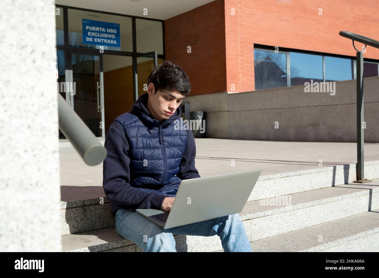 étudiant de l'université, garçon utilisant un ordinateur portable assis sur les escaliers de l'université Banque D'Images