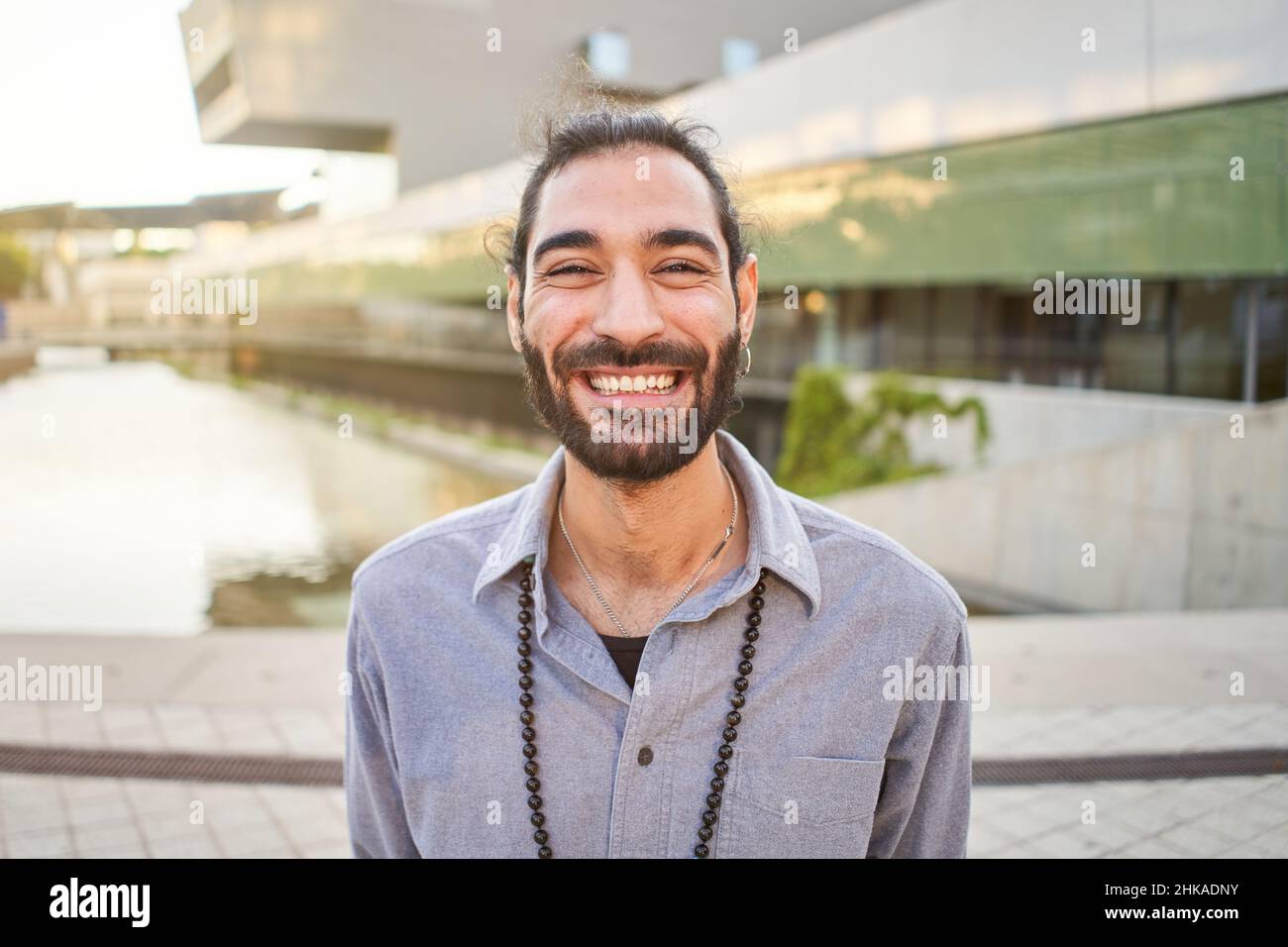 Portrait d'un jeune homme joyeux debout à l'extérieur et souriant à l'appareil photo.Bel homme heureux barbu.Concept d'émotion Banque D'Images
