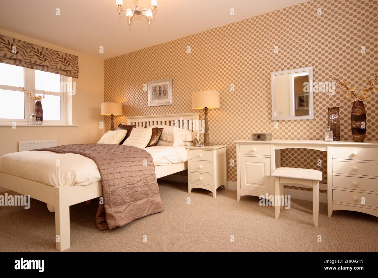 Chambre avec lit double king size surélevé, coiffeuse, lampes de chevet, couvre-lit, jeté de lit, mur Banque D'Images