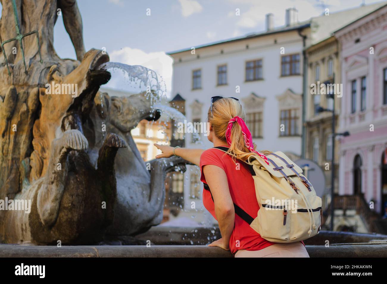 Tourisme à une fontaine de Neptunes dans une ancienne ville d'Olomouc, République tchèque, en été chaud. Femme avec sac à dos est rafraîchissante par l'eau de la fontaine Banque D'Images