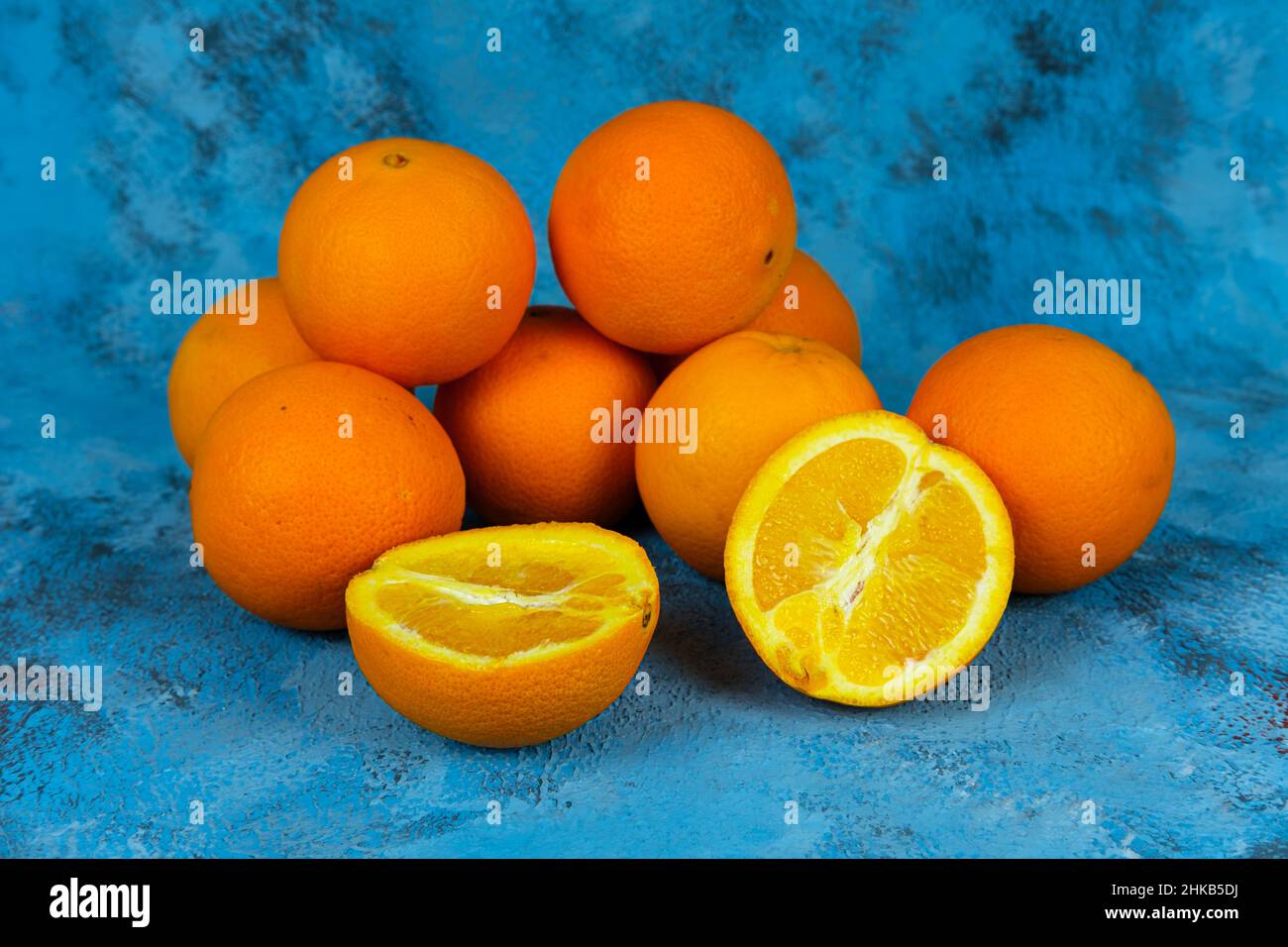 Pile orange sur fond bleu texturé, vue latérale ou profil de beaucoup d'oranges fraîches et lumineuses.Concept de Fruitarianisme sans personne. Banque D'Images