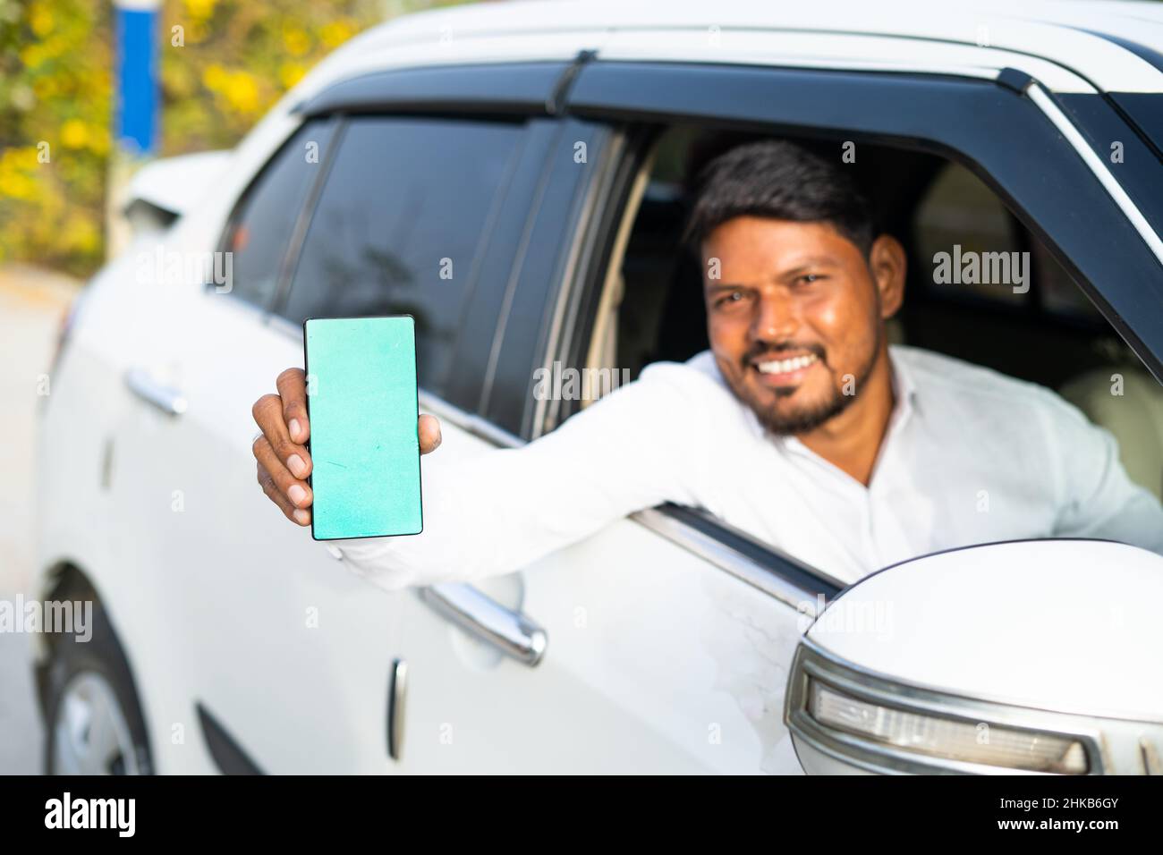 Foucs sur mobile, chauffeur de taxi montrant téléphone mobile avec écran vert maquette en regardant la caméra - concept de réservation en ligne service, publicité d'application Banque D'Images