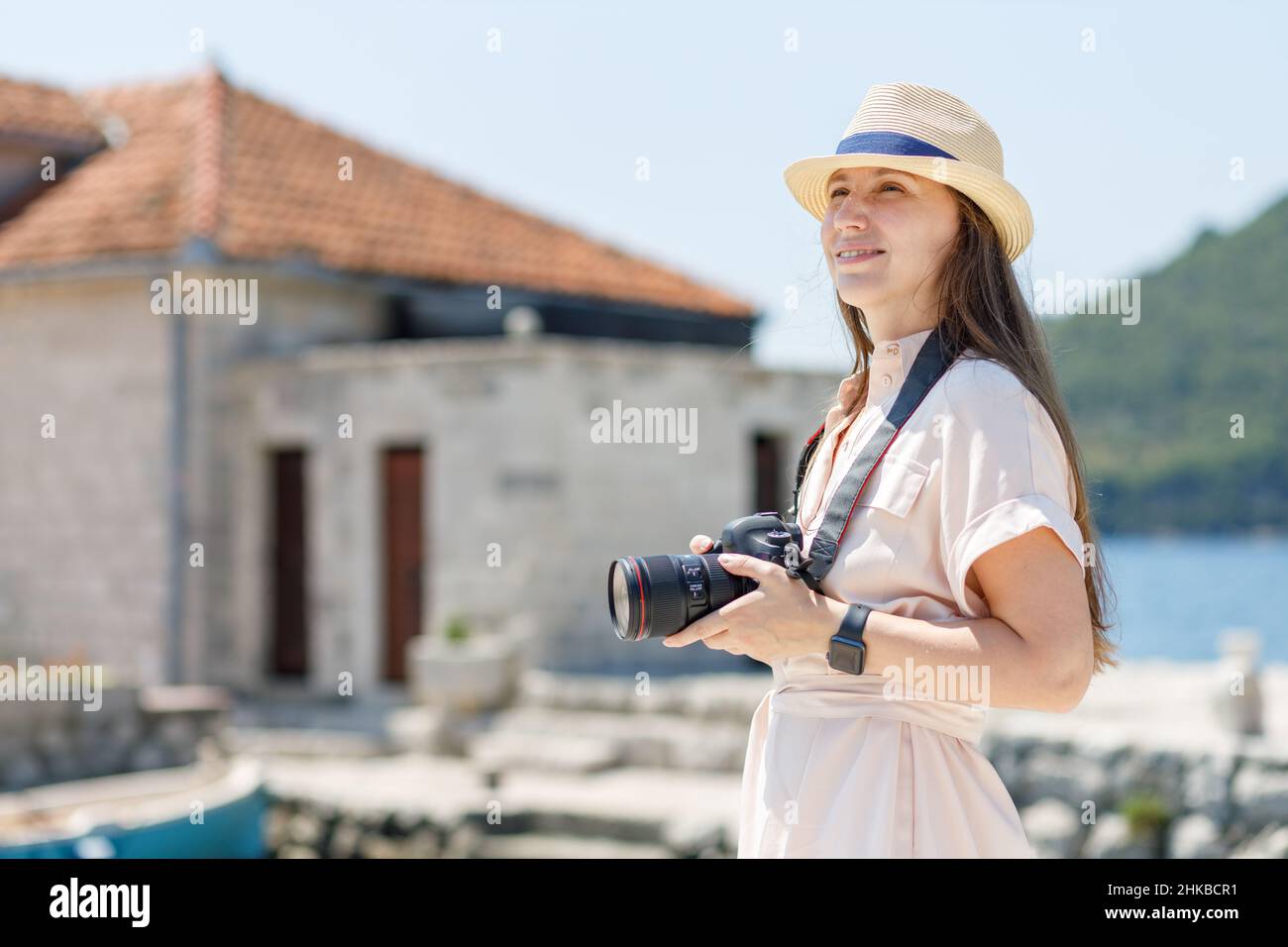 Jeune femme de voyage en robe prend des photos avec un appareil photo professionnel à la journée ensoleillée Banque D'Images