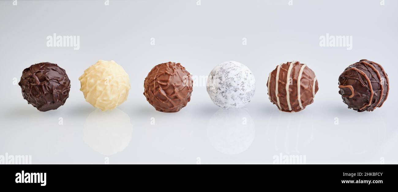 rangée de six truffes au chocolat sur fond blanc avec réflexion, taille de la bannière Banque D'Images