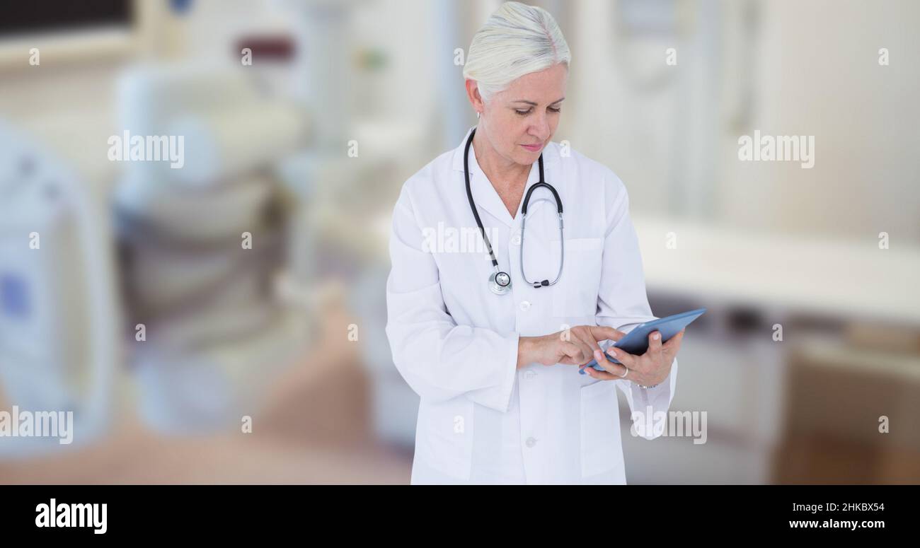 Femme de race blanche mature médecin utilisant une table numérique tout en se tenant dans le théâtre d'opération Banque D'Images