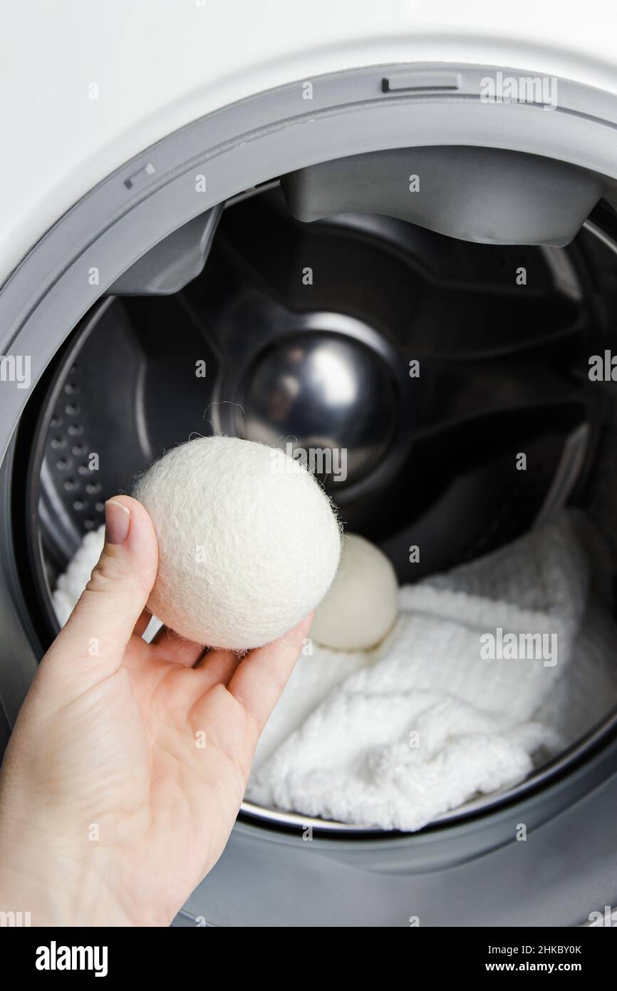 Femme utilisant des balles en laine pour des vêtements plus doux tout en sèche-linge concept en machine à laver.Décharger l'électricité statique et raccourcir le séchage. Banque D'Images