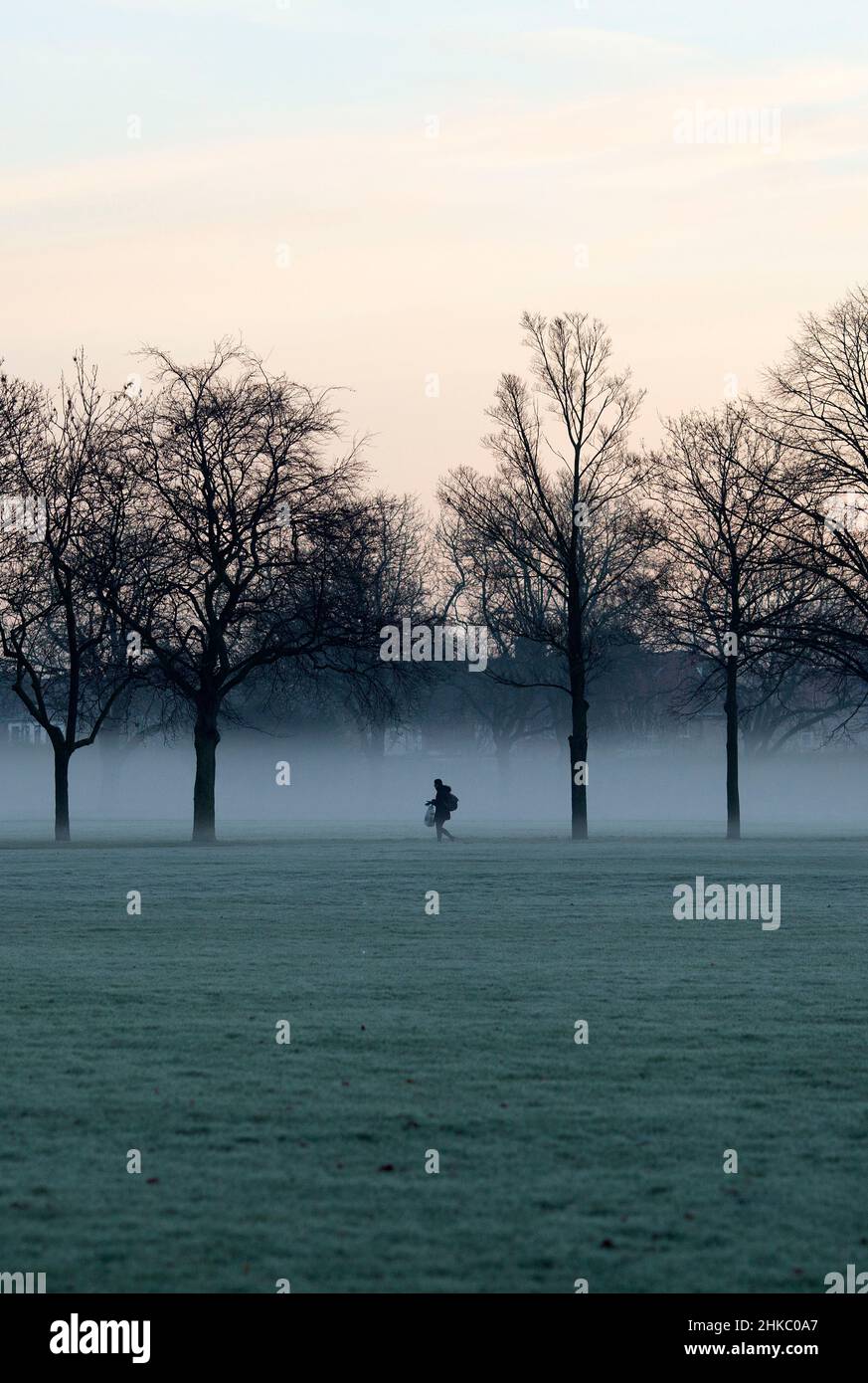 Les piétons marchent dans un parc couvert de brume à Ilford, dans l'est de Londres, le matin, car la température a chuté. Banque D'Images
