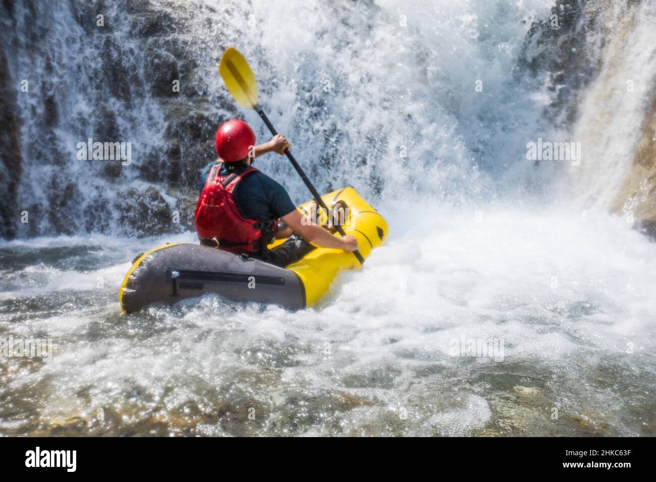 Homme rafting sur une rivière sous une grande cascade en Colombie-Britannique Canada. Banque D'Images