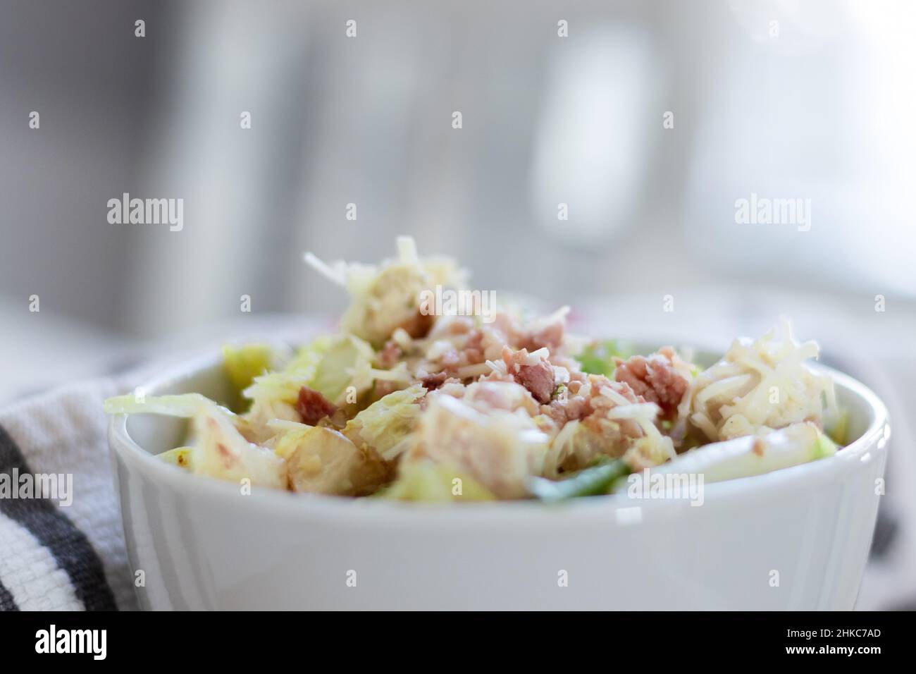 Un gros plan d'une salade de ceaser avec du poulet et du bacon dans un bol blanc. Banque D'Images