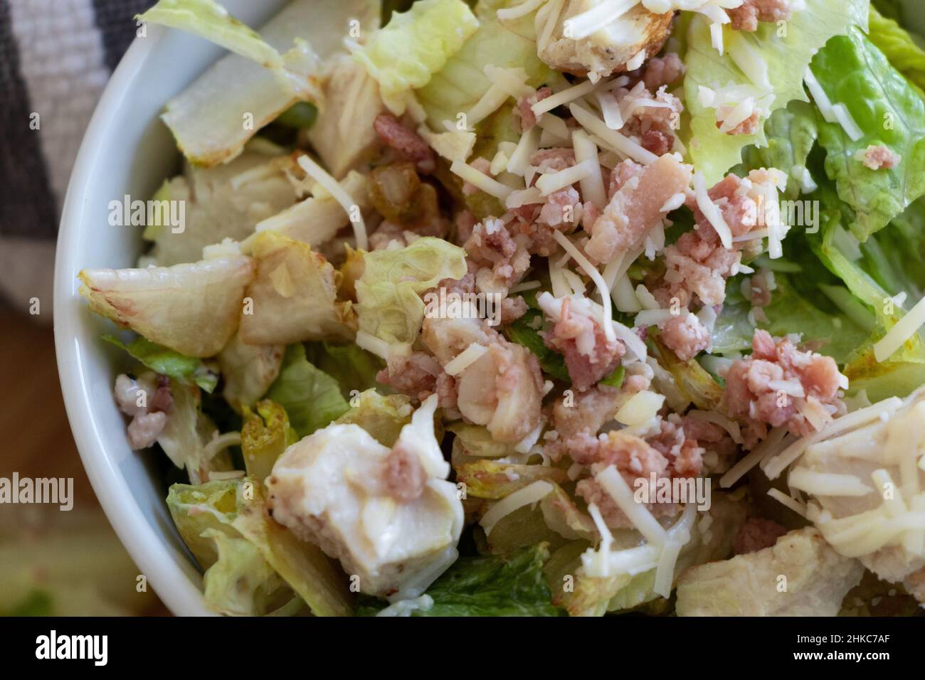 Un gros plan d'une salade de ceaser avec du poulet et du bacon dans un bol blanc. Banque D'Images