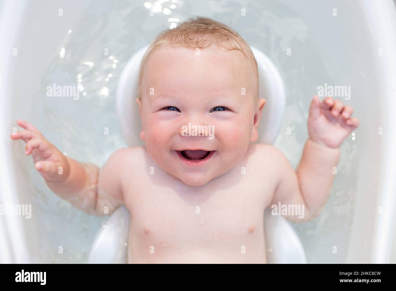 Un bébé joyeux de 6 mois se baigne dans un bain pour bébé Banque D'Images