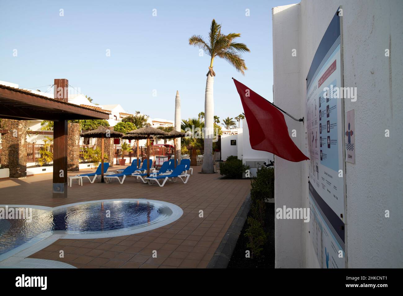 Drapeau rouge à l'extérieur de la piscine dans le complexe hôtelier non surveillé playa blanca Lanzarote Iles Canaries Espagne Banque D'Images