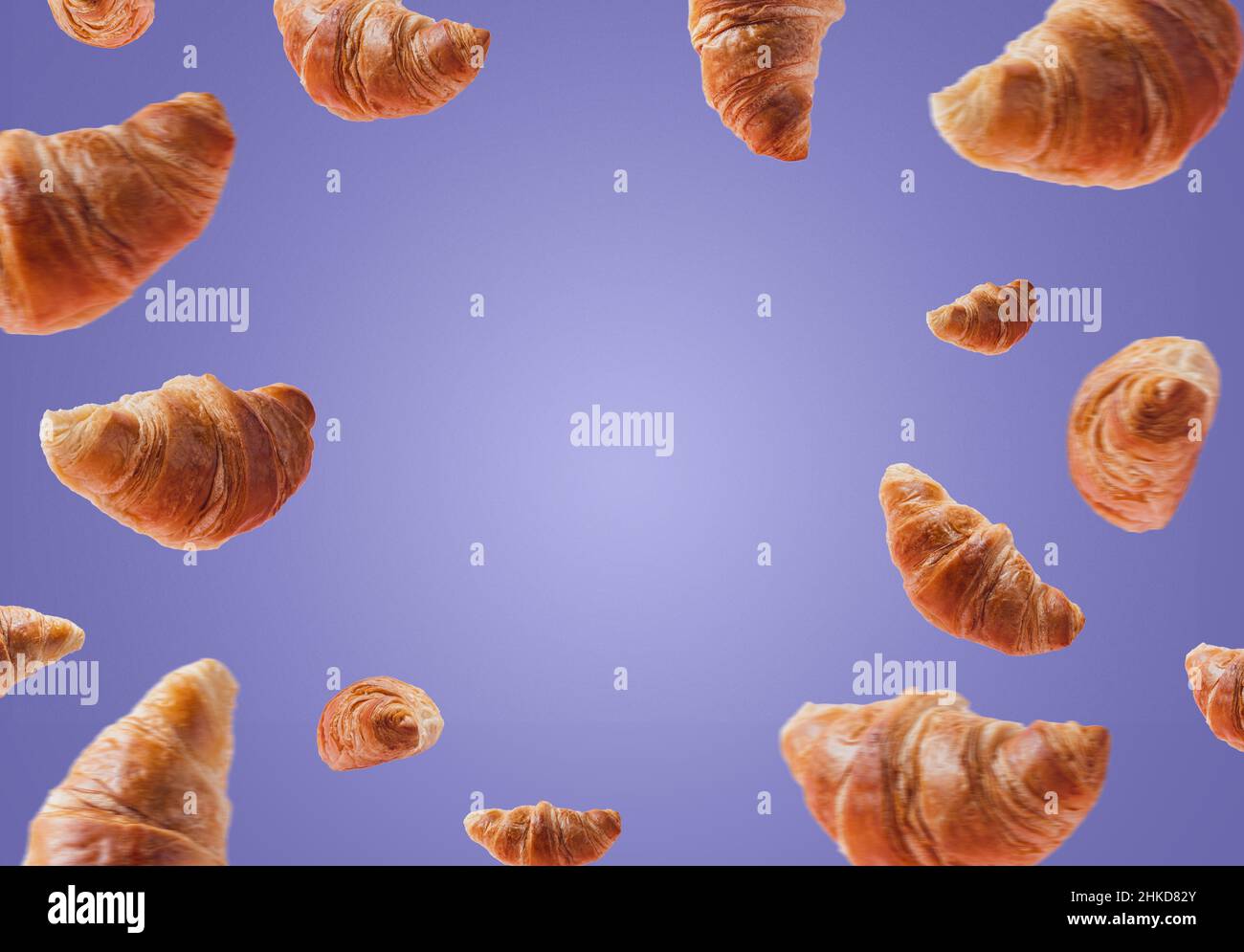 Croissants frais levants ou volants.Un ensemble de croissants volent dans l'air isolé sur fond violet très pery.Copier l'espace.Maquette de panneau, publicité de boulangerie.Petit déjeuner créatif Banque D'Images