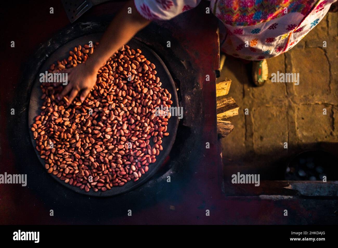 Une femme indigène Amuzgo fait rôtir les fèves de cacao sur une plaque d'argile au feu dans la fabrication artisanale de chocolat à Xochistlahuaca, Guerrero, Mexique. Banque D'Images