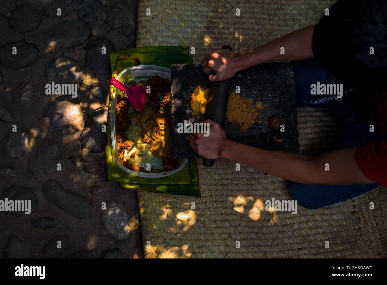 Un homme mexicain grine panela (sucre de canne non raffiné) sur un métate (une pierre de mealing) dans la fabrication artisanale de chocolat à Xochistlahuaca, Mexique. Banque D'Images