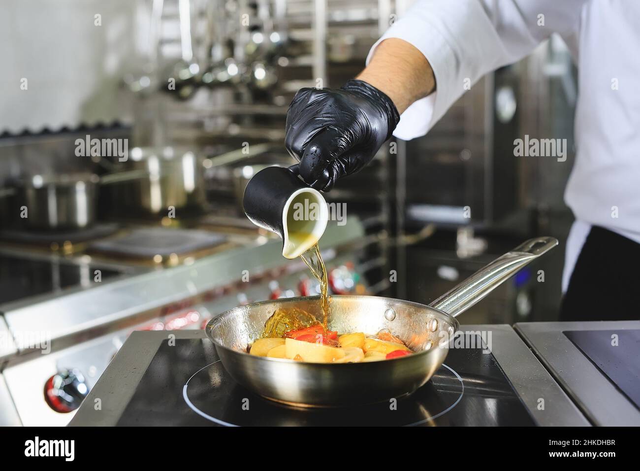Gros plan sur les mains du chef cuisant des aliments au feu.Le chef brûle des aliments dans une cuisine professionnelle Banque D'Images