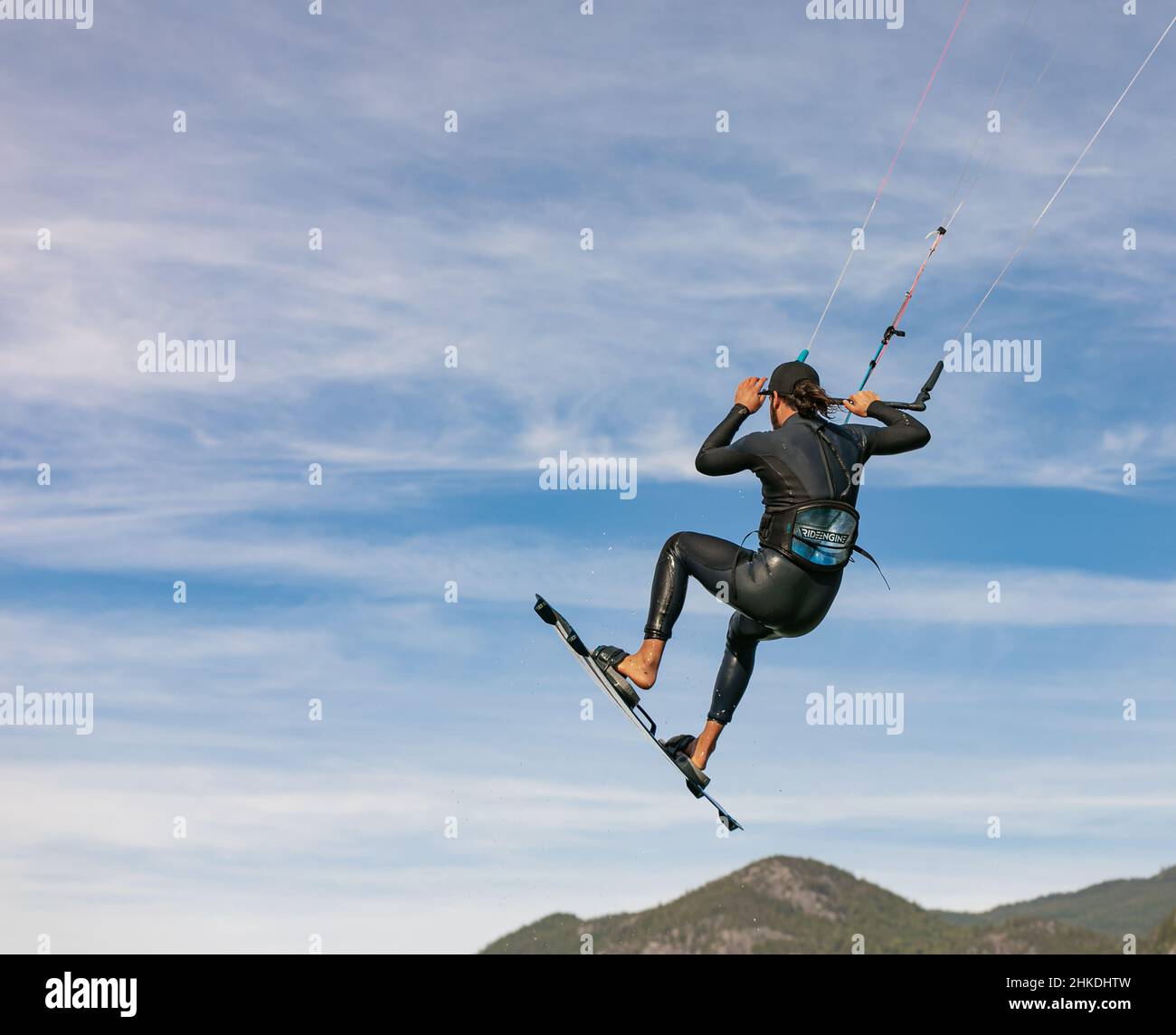 Kite surfeur vole au-dessus du ciel, des montagnes. Kitesurfer saute au-dessus de l'eau lors d'une journée ensoleillée d'été. Homme hobbies et loisirs kitesurf, kiteboarding-Ju Banque D'Images