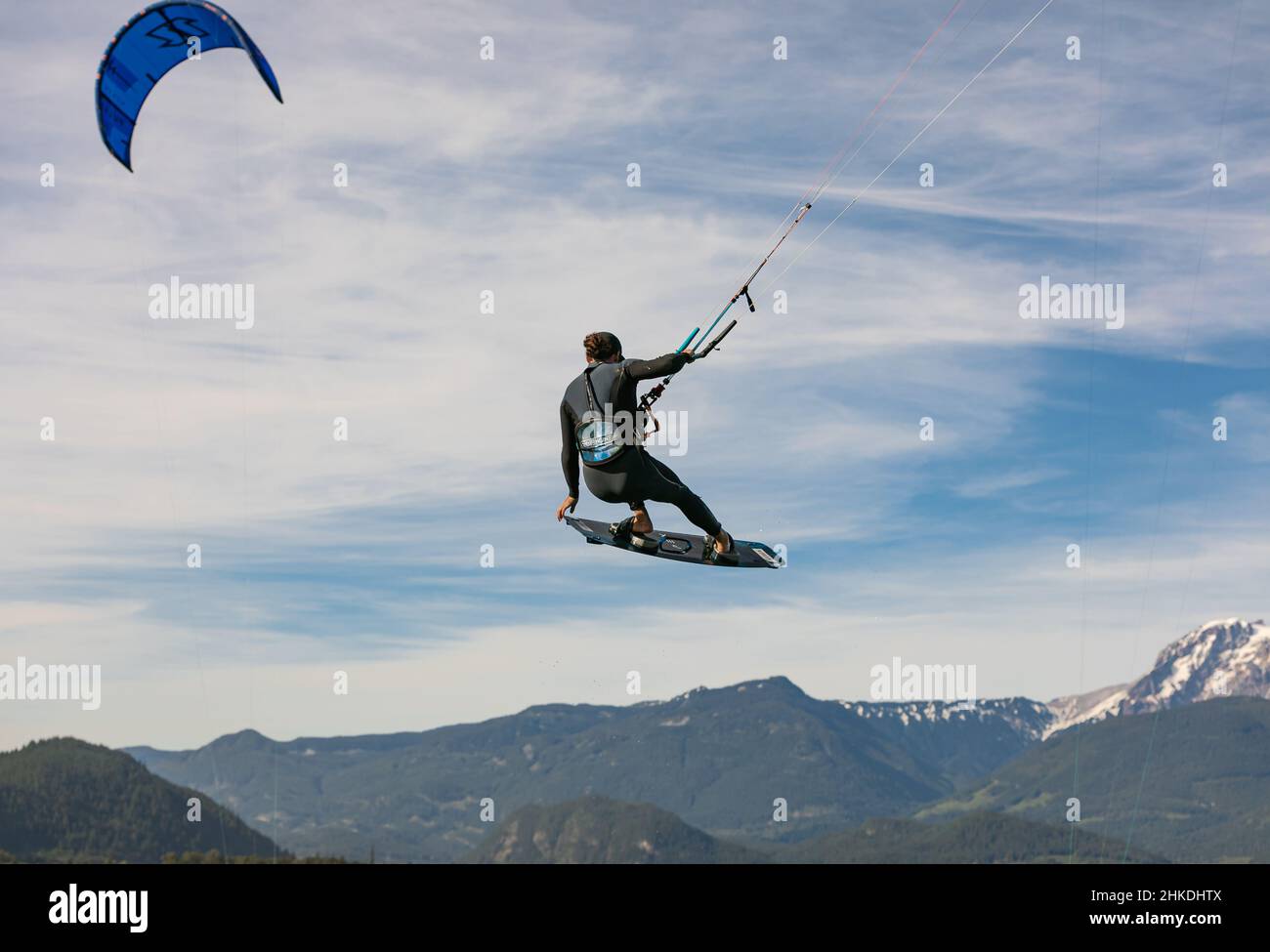 Kite surfeur vole au-dessus du ciel, des montagnes. Kitesurfer saute au-dessus de l'eau lors d'une journée ensoleillée d'été. Homme hobbies et loisirs kitesurf, kiteboarding-Ju Banque D'Images