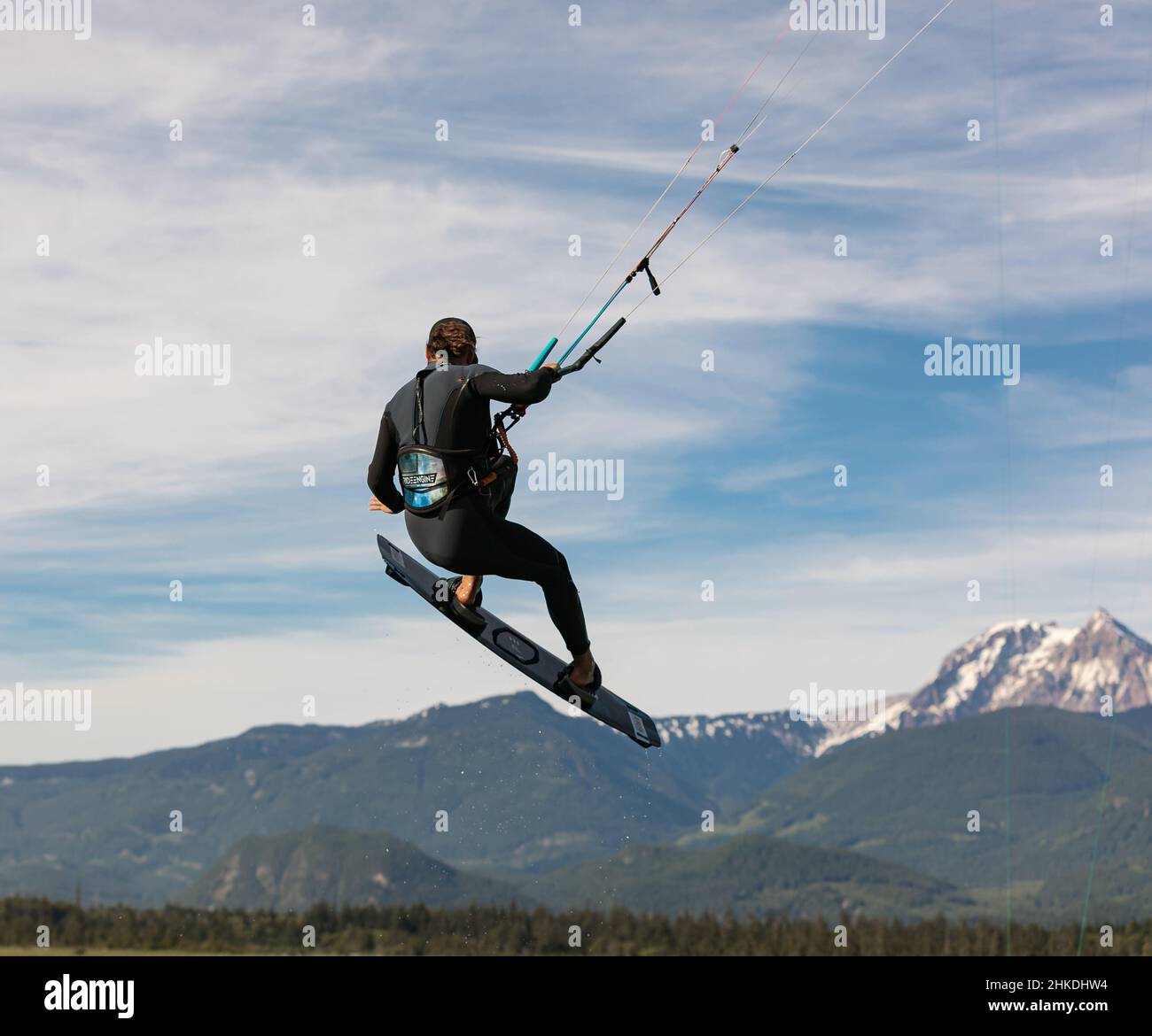Kite surfeur vole au-dessus du ciel, des montagnes. Kitesurfer saute au-dessus de l'eau lors d'une journée ensoleillée d'été. Homme hobbies et loisirs kitesurf, kiteboarding-Ju Banque D'Images