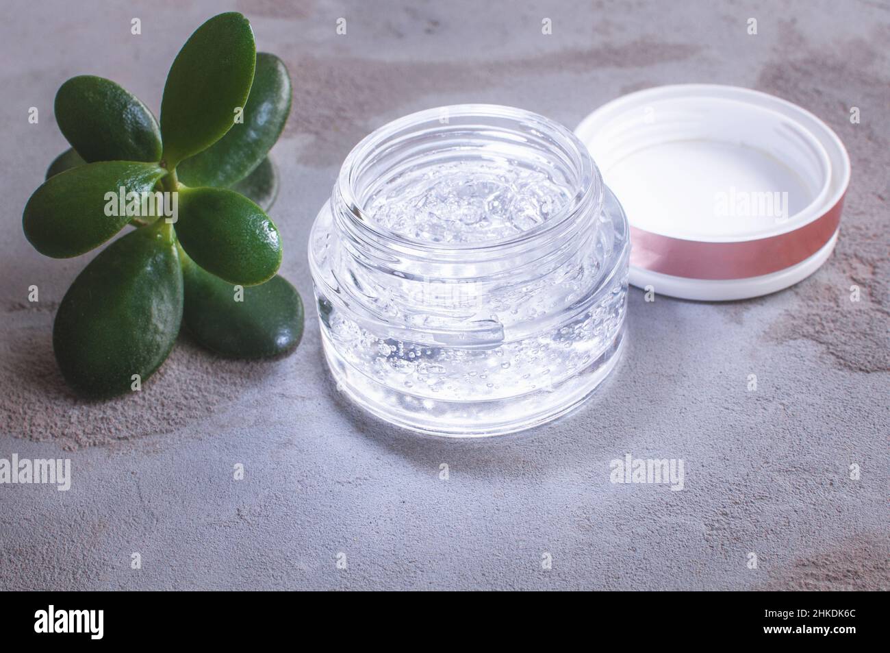 pot transparent avec gel hydratant et acide hyaluronique sur fond de béton Banque D'Images