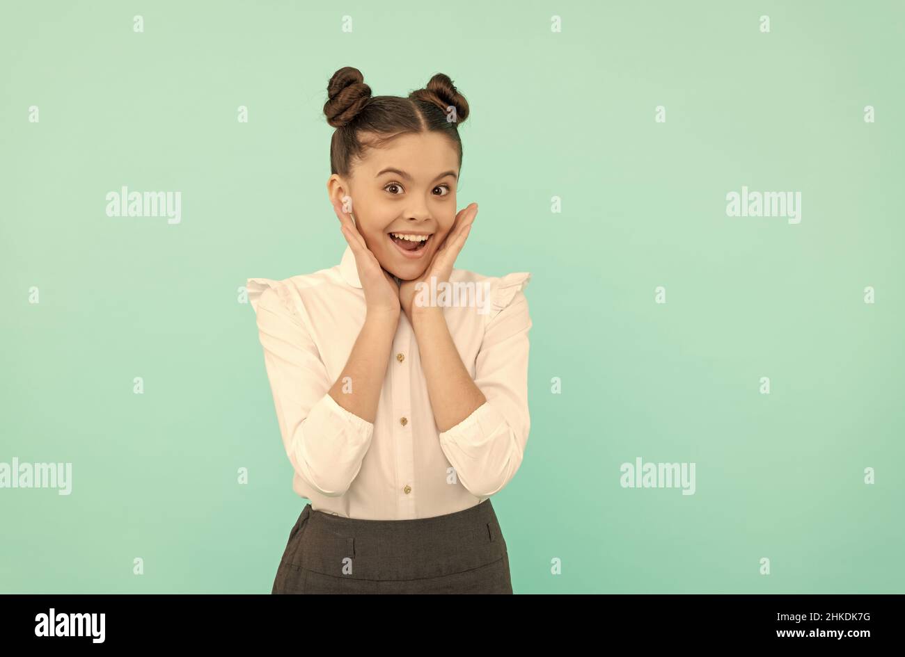 Bonne adolescente de retour à l'école touchant le visage peau fond bleu, soin de la peau Banque D'Images