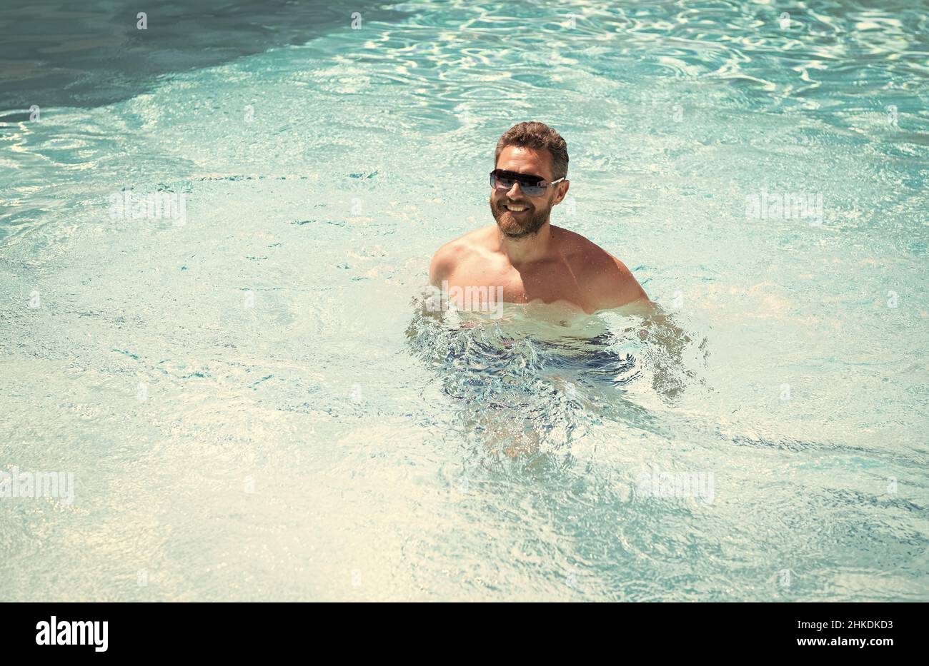 joyeux barbu dans des lunettes de soleil, détendez-vous dans la piscine de la station thermale pendant les vacances d'été, l'été. Banque D'Images