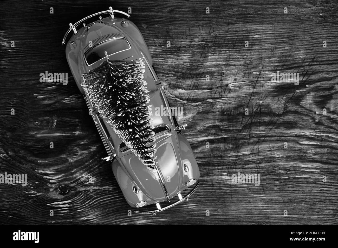 Voiture jouet avec épicéa sur le toit, sur fond de bois, vue du dessus.décorations de Noël et du nouvel an.photo noir et blanc Banque D'Images