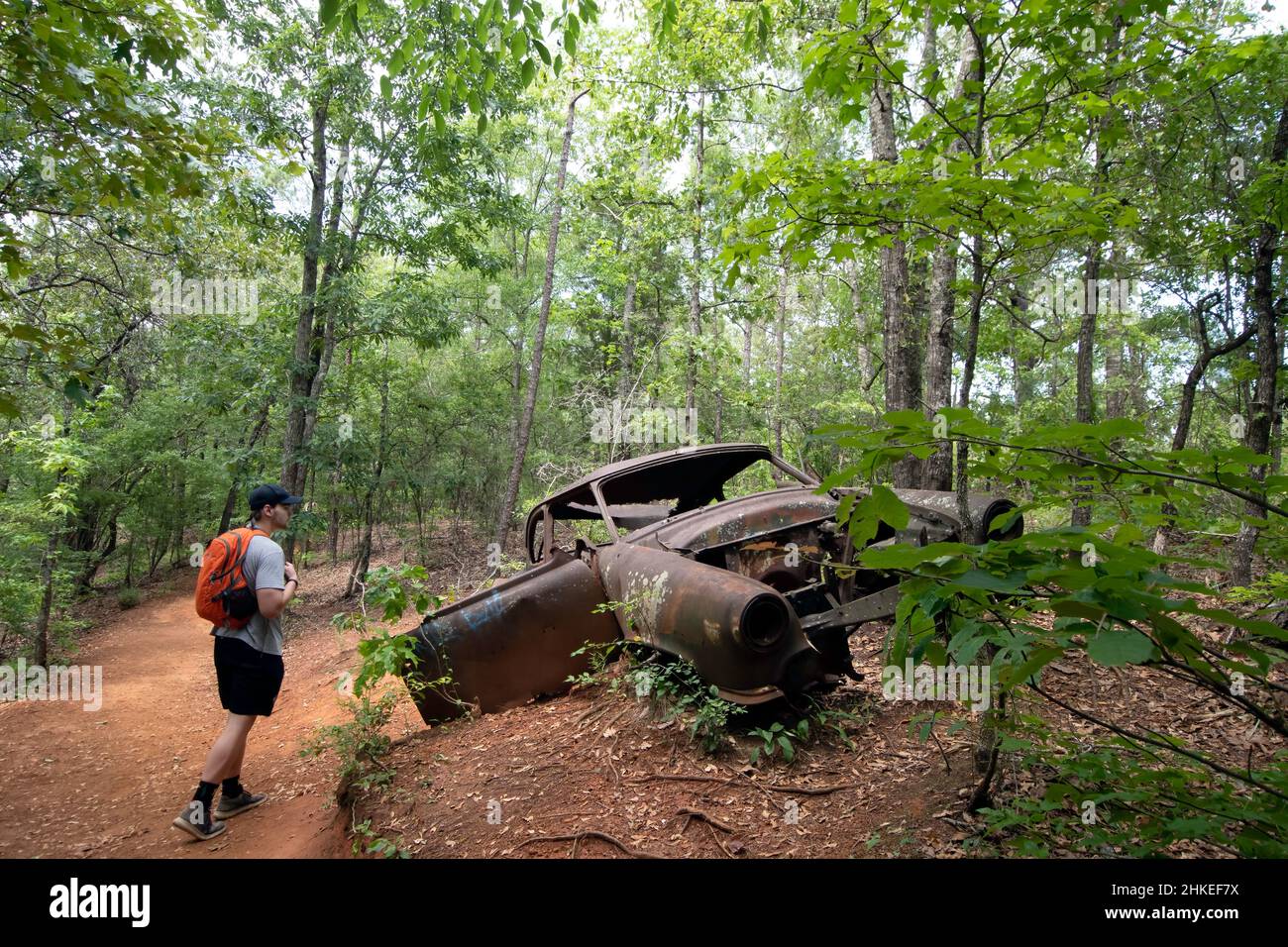 Lumpkin, Géorgie, États-Unis- 6 juin 2021 : ancienne voiture abandonnée sur le site d'une ancienne ferme avec un randonneur mâle regardant le parc national de Providence Canyon dans les s Banque D'Images