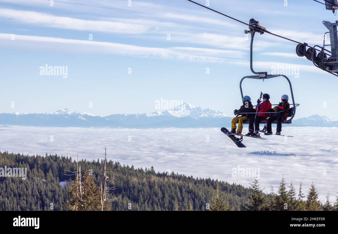 Personnes sur un télésiège à la station de ski de Grouse Mountain avec mnt Baker en arrière-plan Banque D'Images