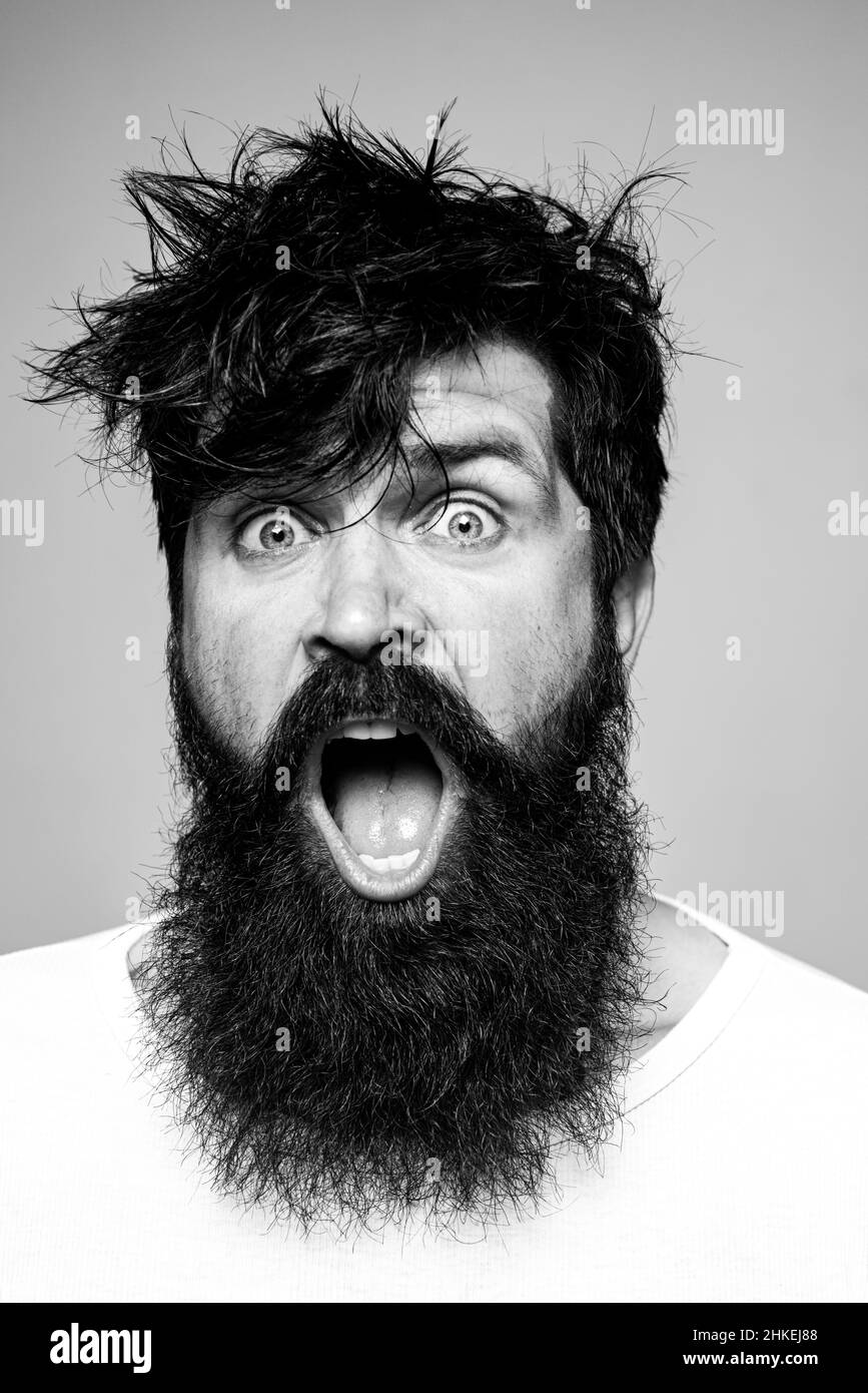 Homme à la barbe et à la moustache, il a l'air émerveillé et enthousiaste.  Coupe de cheveux pour homme, style moderne. Gros plan sur un modèle  masculin avec des cheveux longs. Soins