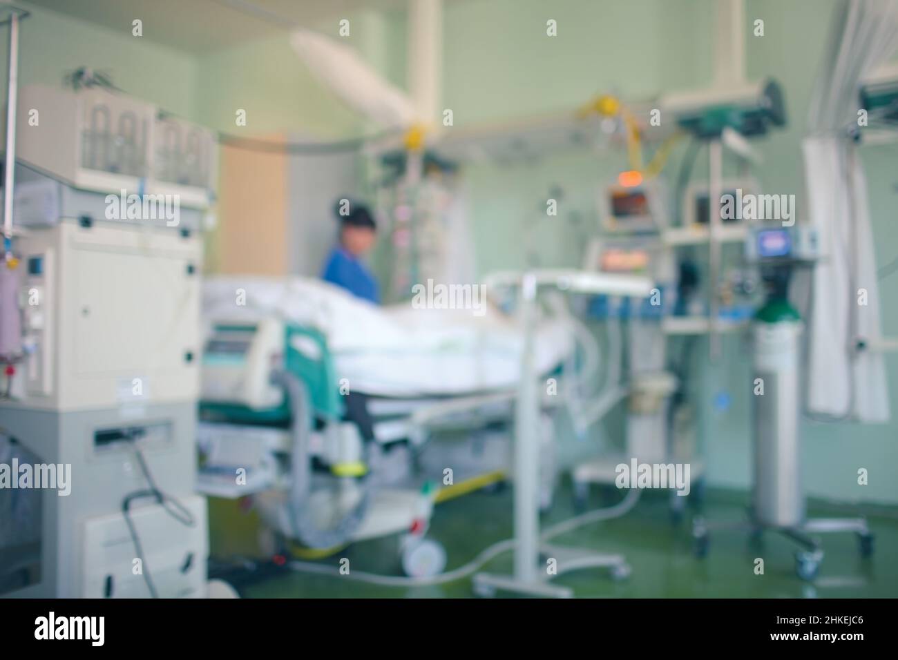 Patient gravement malade entouré de technologies médicales en USI.Une femme médecin se tient près du lit du patient et travaille avec l'équipement.Arrière-plan non focalisé Banque D'Images