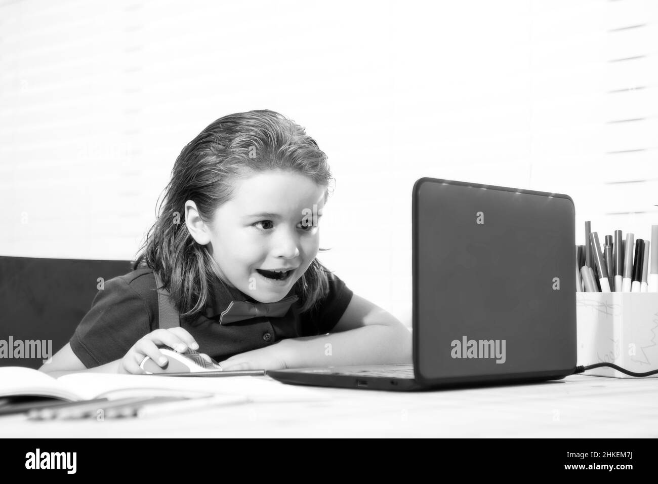 Garçon d'école avec un visage souriant étudiant et utilisant un ordinateur portable et écrivant sur un ordinateur portable. Nerd drôle élève. Banque D'Images