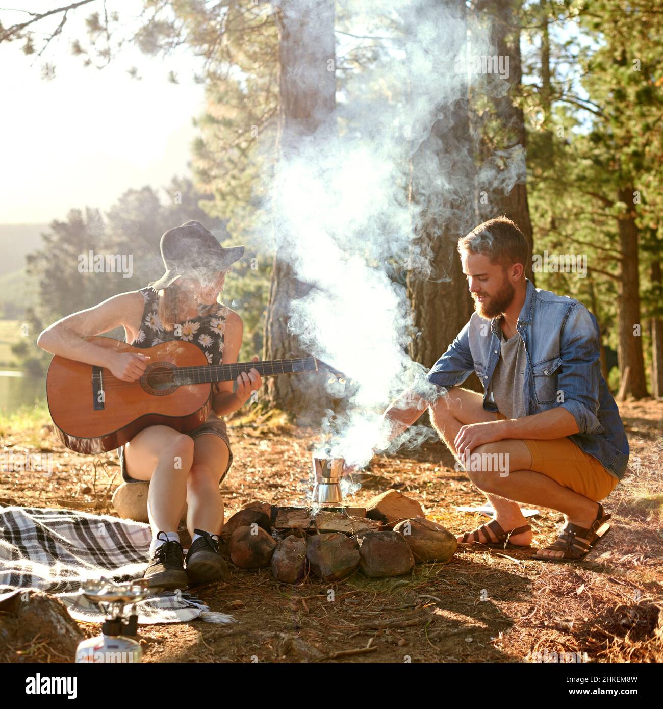 Chansons de feu de camp.Prise de vue d'une jeune femme jouant de la guitare pour son petit ami à leur campement. Banque D'Images