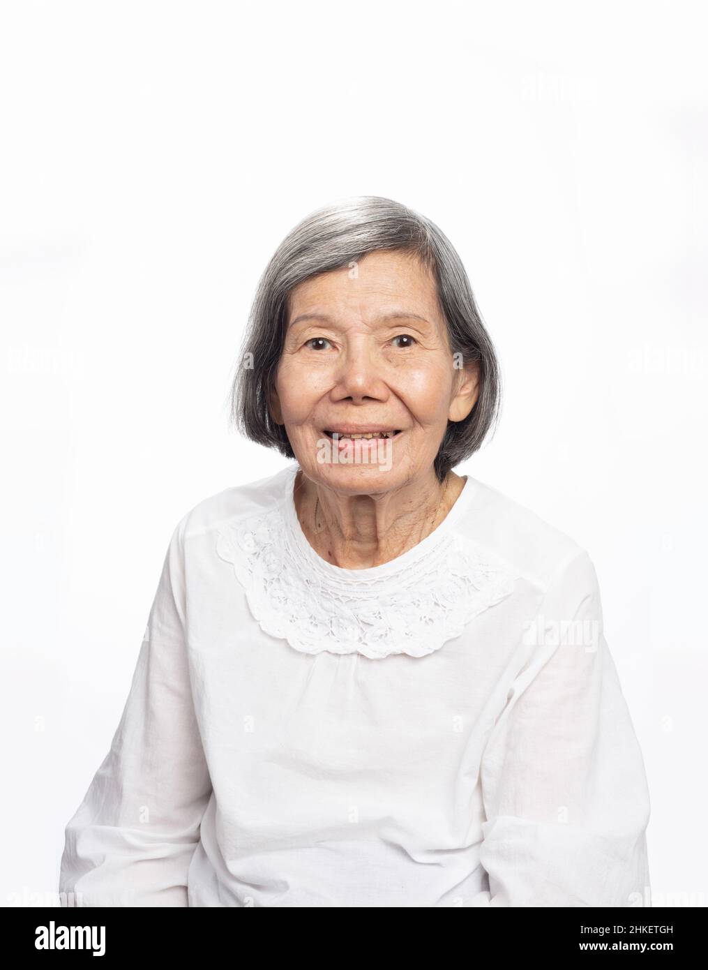 Portrait d'une femme asiatique âgée, mignonne et souriante, regardant un appareil photo isolé sur blanc.Une vieille dame mûre gros plan. Banque D'Images