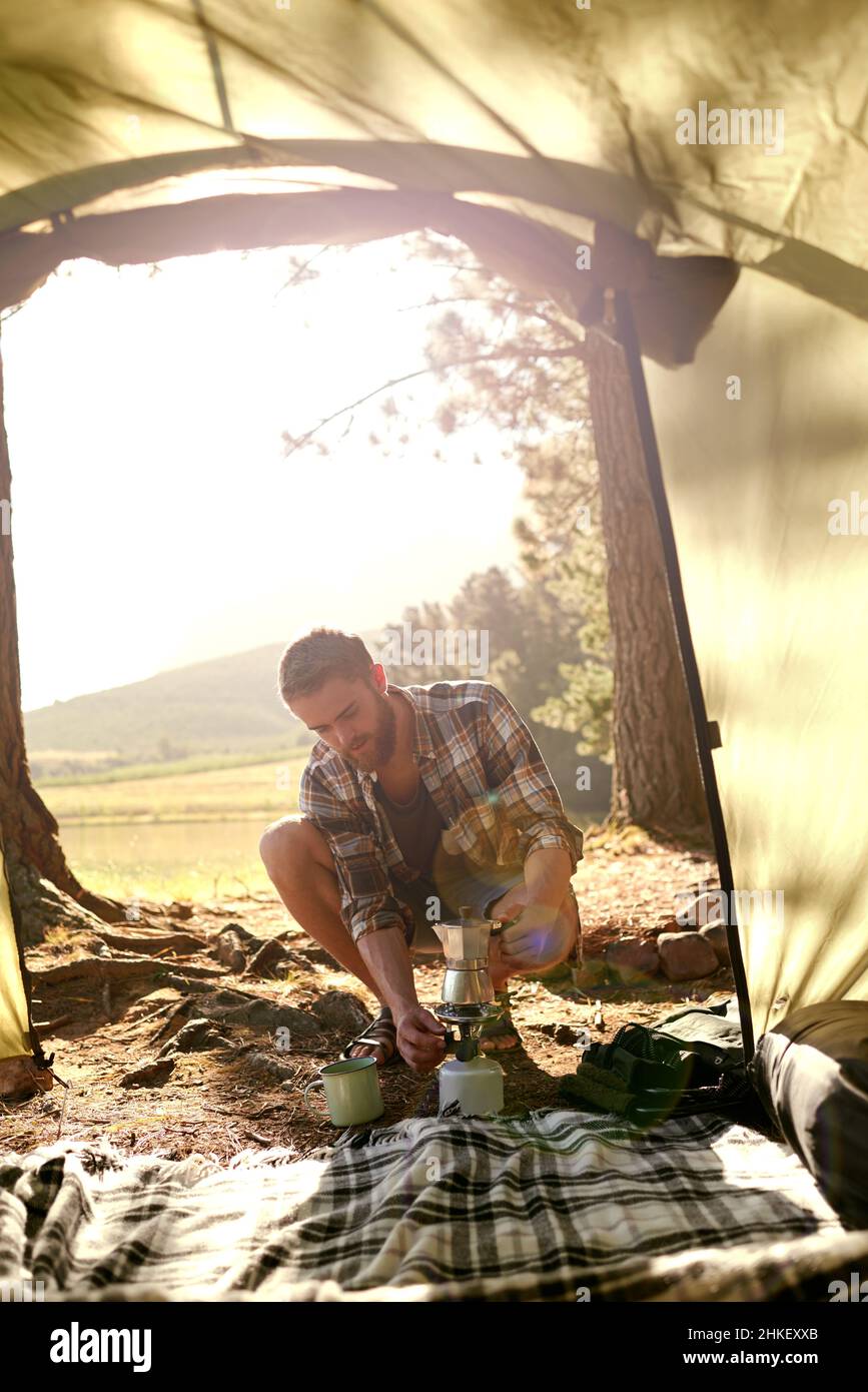 Dans les bois.Photo d'un jeune homme faisant du café sur un poêle de camp pendant le camping. Banque D'Images