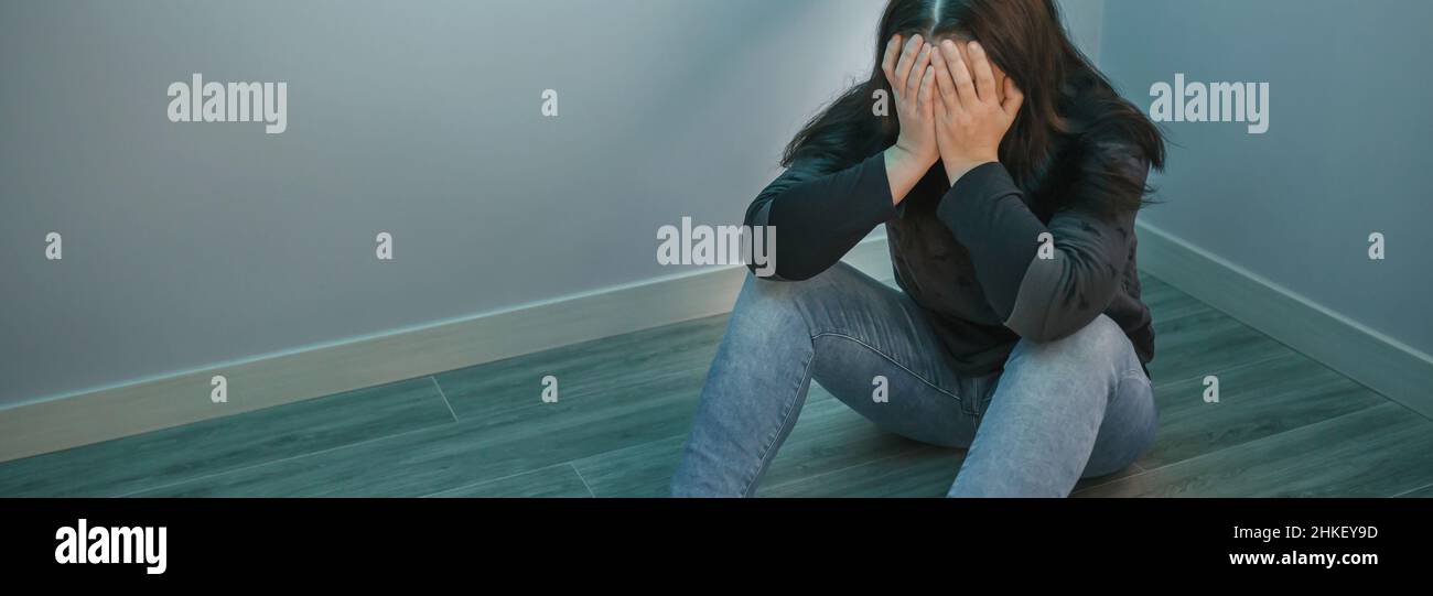 Femme dépressive méconnue avec les mains dans le visage assis sur le sol Banque D'Images