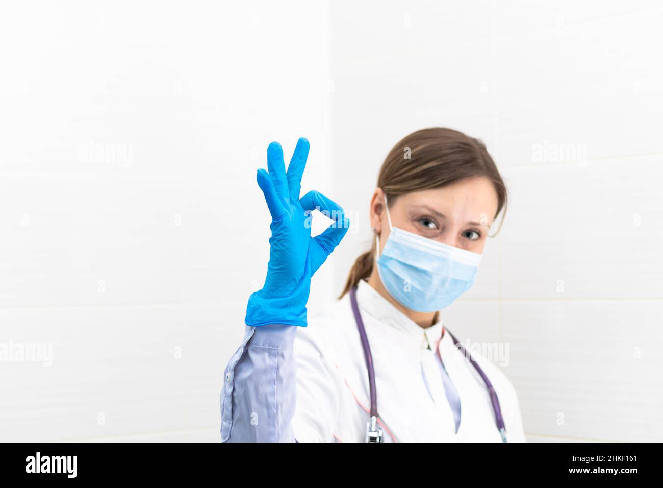 Belle jeune femme médecin dans un masque médical et des gants avec un stéthoscope à l'hôpital montre des gestes de main.Mise au point sélective.Portrait.Gros plan Banque D'Images