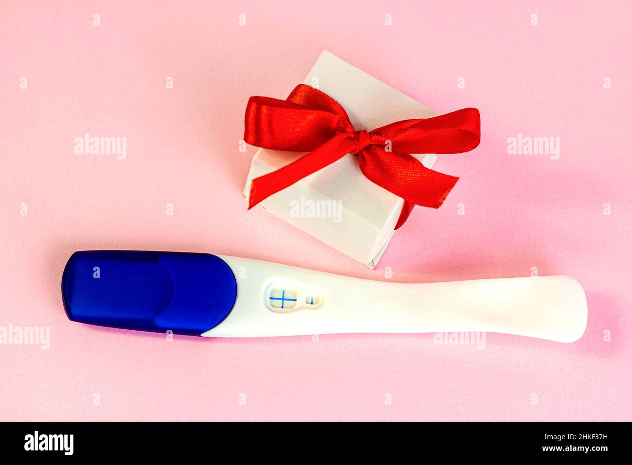 Test de grossesse positif avec boîte cadeau sur fond rose clair.Concept de  planification de naissance de bébé et d'attente d'enfant Photo Stock - Alamy