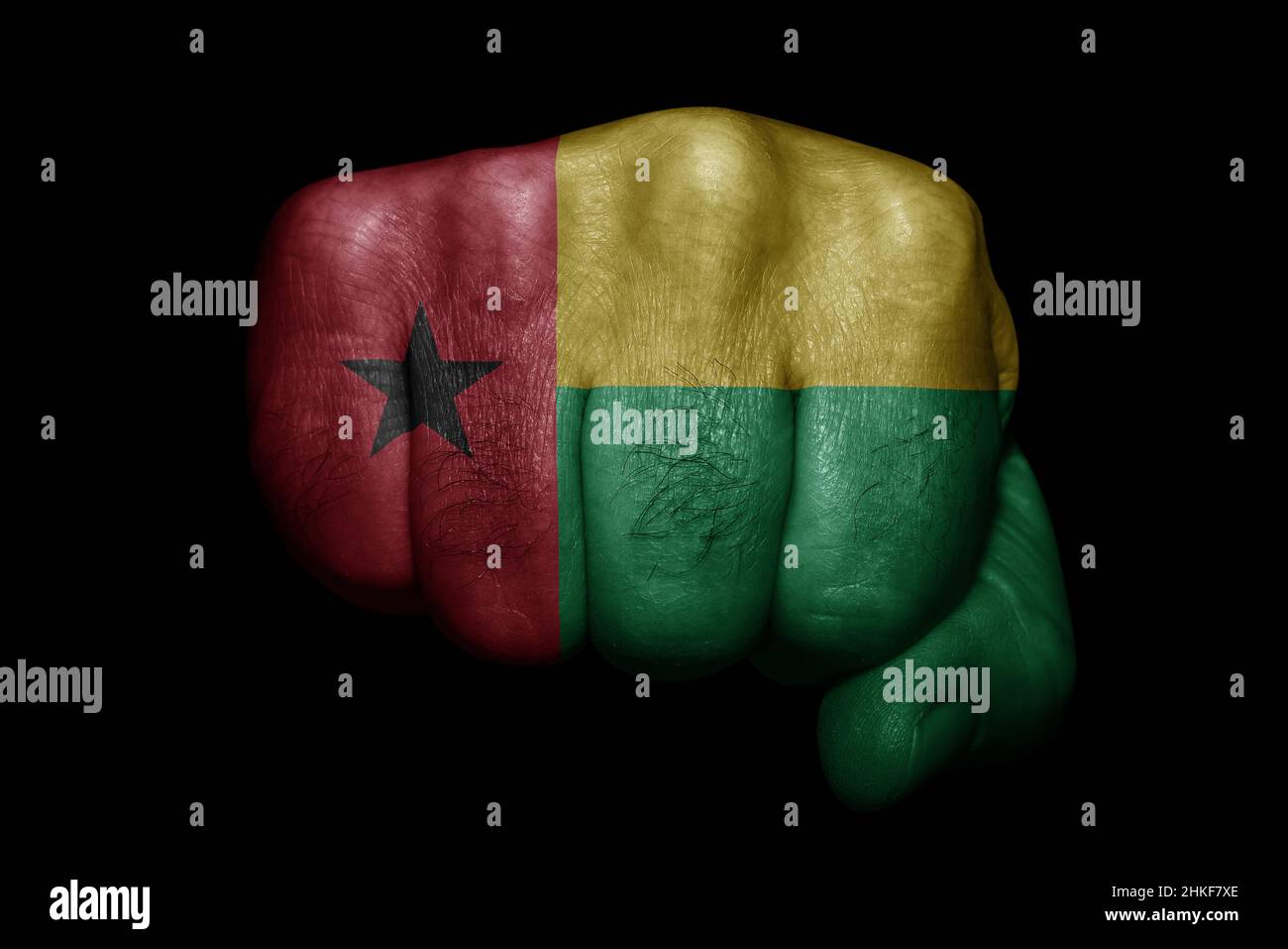 Drapeau de la Guinée-Bissau peint sur un poing fort sur fond noir Banque D'Images Drapeau de la Guinée-Bissau peint sur un poing fort sur fond noir Banque D'Images