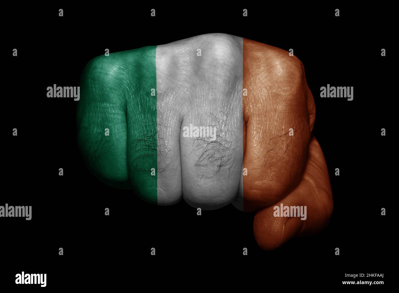 Drapeau de l'Irlande peint sur un poing fort sur fond noir Banque D'Images Drapeau de l'Irlande peint sur un poing fort sur fond noir Banque D'Images