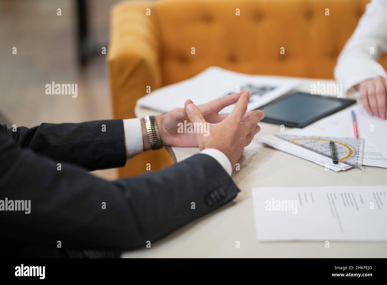 Les mains des hommes dans une veste noire sur le bureau avec beaucoup de documents papier et tablette pc en face de lui.Entretien d'un nouveau chef de projet avec un homme d'affaires maki.Gros plan sur les mains. Banque D'Images