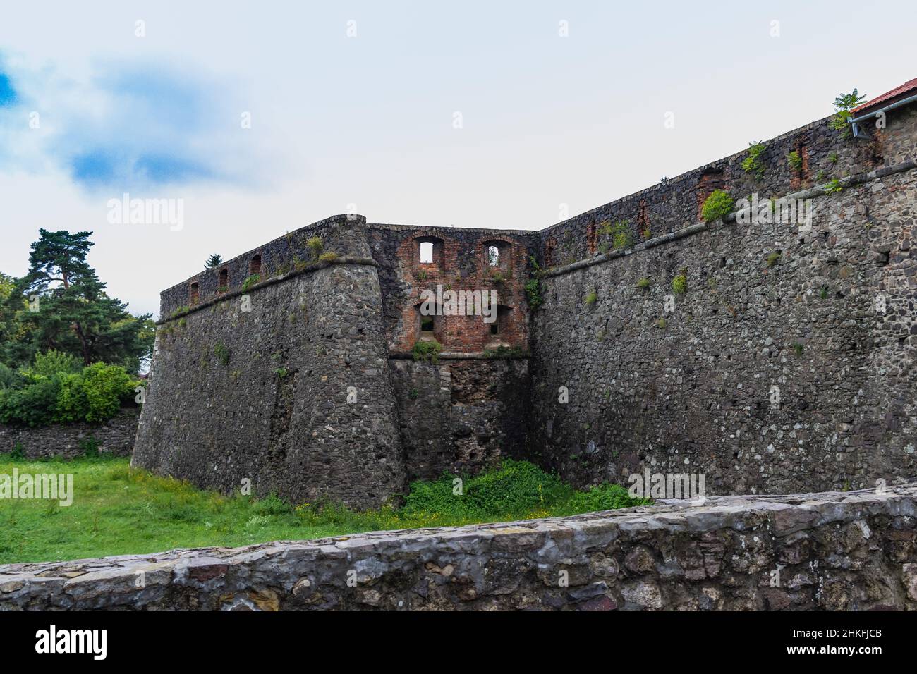 Mur médiéval du château gris de l'ancien château d'Uzhgorod avec une pelouse verte devant. Château d'Uzhgorod, région de Zakarpattya, Ukraine occidentale Banque D'Images