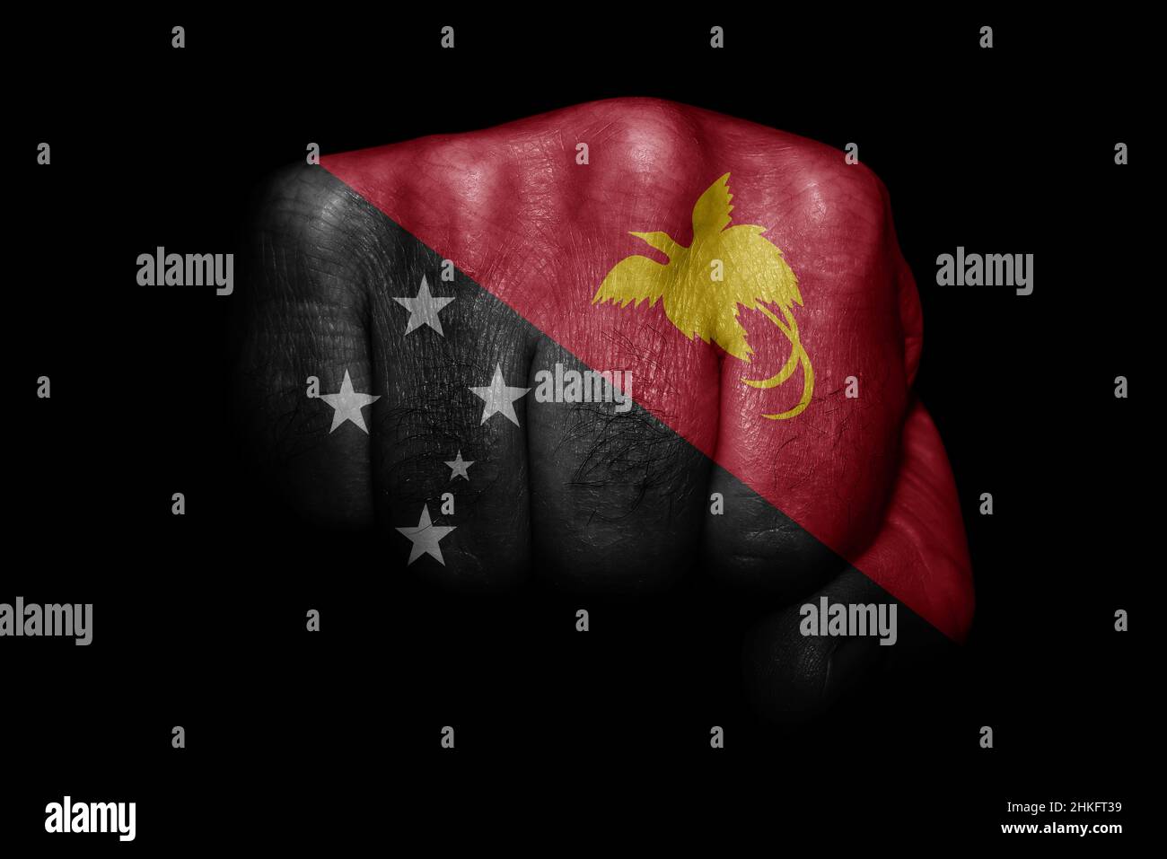Drapeau de la Papouasie-Nouvelle-Guinée peint sur un fort poing sur fond noir Banque D'Images Drapeau de la Papouasie-Nouvelle-Guinée peint sur un fort poing sur fond noir Banque D'Images