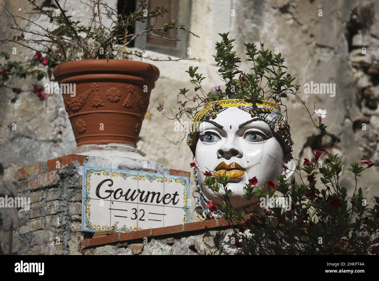 Italie, Sicile, Taormina, pot de fleurs en céramique représentant une tête mauresque pose sur un mur dans le centre médiéval Banque D'Images