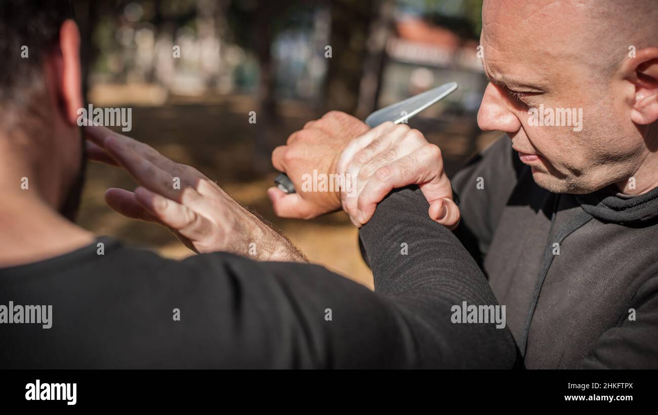 Menace de couteau.L'instructeur de Kapap démontre la technique de désarmement d'auto-défense des arts martiaux contre l'attaque au couteau.Formation de désarmement des armes.Démonstration Banque D'Images