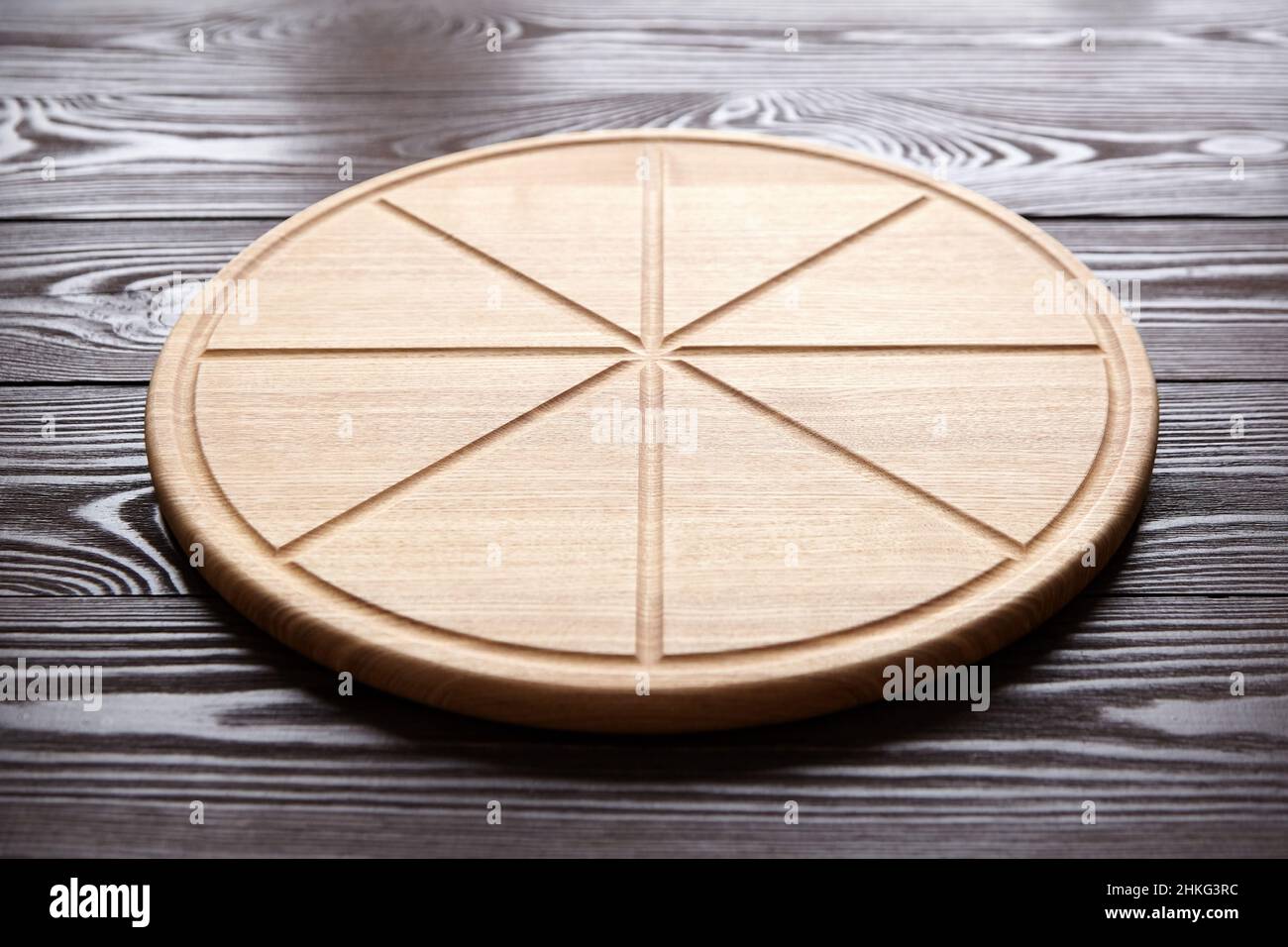 Planche à découper ronde pour pizza avec rainures en tranches sur une table en bois brun Banque D'Images