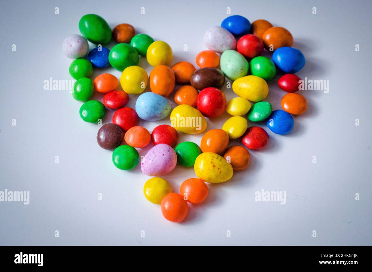 Petits bonbons multicolores en forme de cœur sur fond blanc avec espace pour écrire du texte Banque D'Images