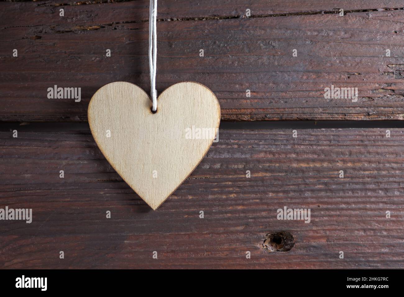 Suspension en forme de coeur naturel sur un mur en bois rustique sombre, symbole de l'amour dans la vie quotidienne et les vacances comme les valentines, la fête des mères, le jour du père et b Banque D'Images