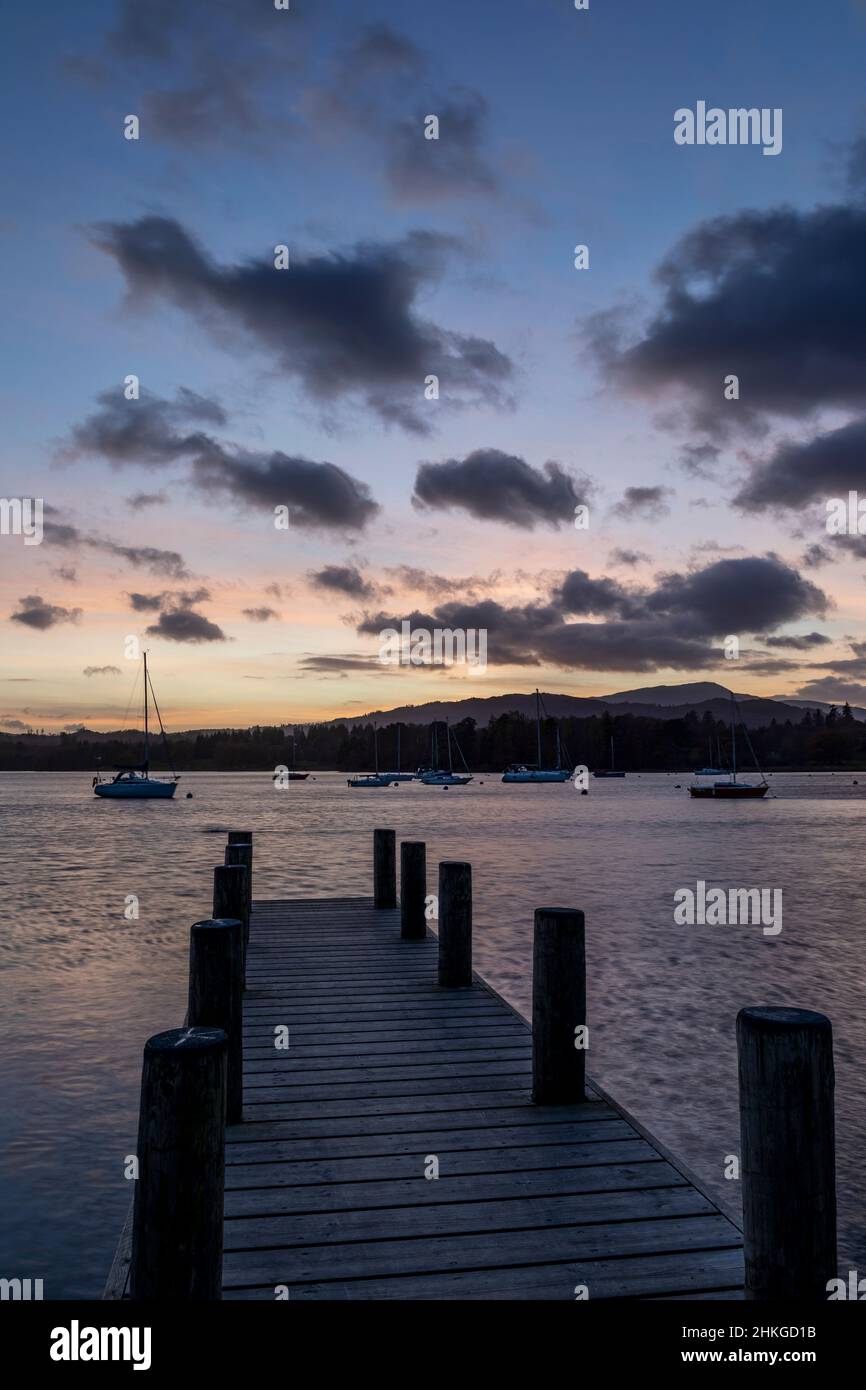 coucher de soleil sur le lac windermere avec jetée et bateaux à l'ancre Banque D'Images