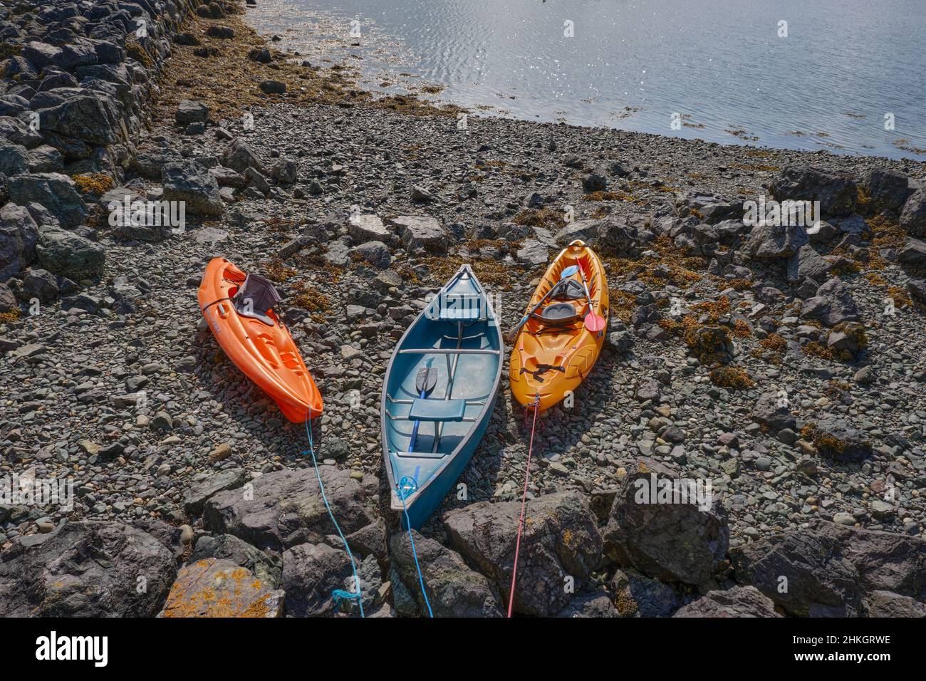 Trois kayaks colorés amarrés sur une plage rocheuse à Porth Dinllaen, pays de Galles Banque D'Images